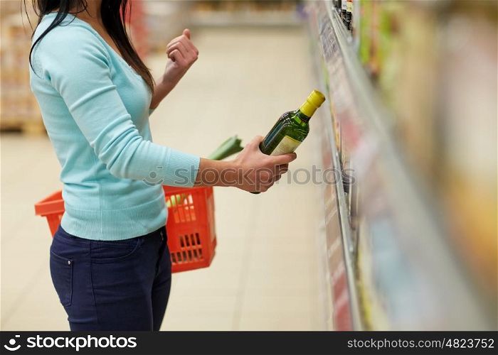 sale, shopping, food, consumerism and people concept - woman buying olive oil at grocery store or supermarket