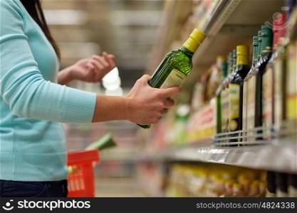 sale, shopping, food, consumerism and people concept - woman buying olive oil at grocery store or supermarket