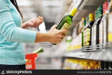 sale, shopping, food, consumerism and people concept - woman buying olive oil at grocery store or supermarket. woman buying olive oil at supermarket or grocery. woman buying olive oil at supermarket or grocery