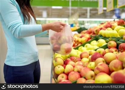 sale, shopping, food, consumerism and people concept - woman holding bag with apples at grocery store. woman with bag buying apples at grocery store