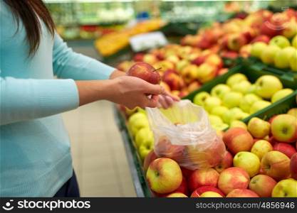 sale, shopping, food, consumerism and people concept - woman with bag buying apples at grocery store