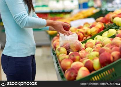 sale, shopping, food, consumerism and people concept - woman with bag buying apples at grocery store. woman with bag buying apples at grocery store