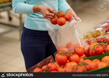 sale, shopping, food, consumerism and people concept - woman with bag buying tomatoes at grocery store