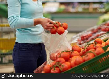 sale, shopping, food, consumerism and people concept - woman with bag buying tomatoes at grocery store