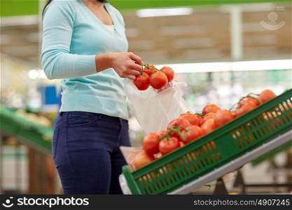 sale, shopping, food, consumerism and people concept - woman with bag buying tomatoes at grocery store. woman with bag buying tomatoes at grocery store