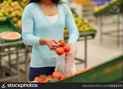 sale, shopping, food, consumerism and people concept - woman with bag buying tomatoes at grocery store. woman with bag buying tomatoes at grocery store. woman with bag buying tomatoes at grocery store