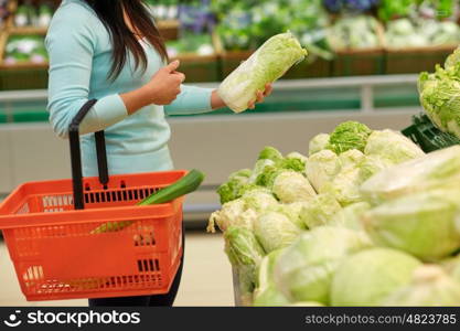 sale, shopping, food, consumerism and people concept - woman with basket buying chinese cabbage at grocery store