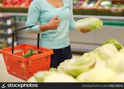 sale, shopping, food, consumerism and people concept - woman with basket buying chinese cabbage at grocery store