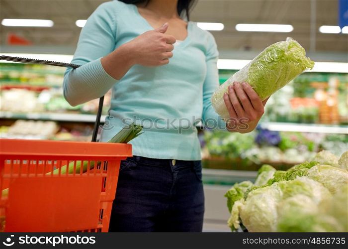 sale, shopping, food, consumerism and people concept - woman with basket buying chinese cabbage at grocery store