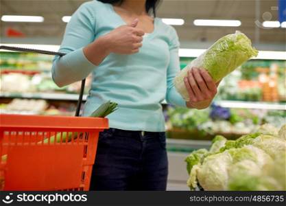 sale, shopping, food, consumerism and people concept - woman with basket buying chinese cabbage at grocery store