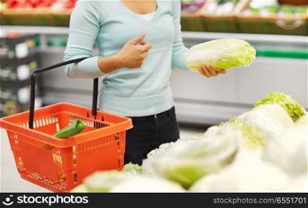 sale, shopping, food, consumerism and people concept - woman with basket buying chinese cabbage at grocery store. woman with basket and chinese cabbage at grocery. woman with basket and chinese cabbage at grocery