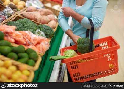 sale, shopping, food, consumerism and people concept - woman with basket buying broccoli at grocery store. woman with basket buying broccoli at grocery store