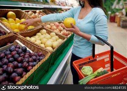 sale, shopping, food, consumerism and people concept - woman with basket buying pomelo at grocery store