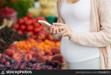 sale, shopping, food, pregnancy and people concept - close up of pregnant woman with smartphone at street market