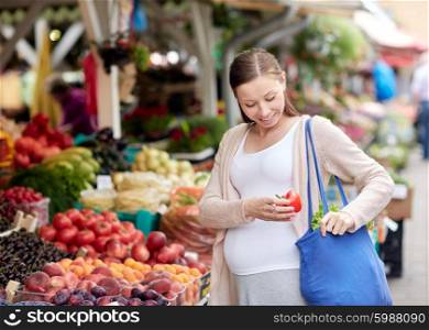 sale, shopping, food, pregnancy and people concept - happy pregnant woman buying red pepper or paprika at street market