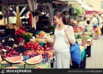 sale, shopping, food, pregnancy and people concept - happy pregnant woman with bag holding tomato at street market