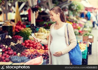 sale, shopping, food, pregnancy and people concept - happy pregnant woman with smartphone at street market