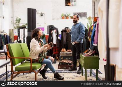 sale, shopping, footwear and people concept - happy couple choosing loafer shoes at vintage clothing store. couple choosing footwear at vintage clothing store