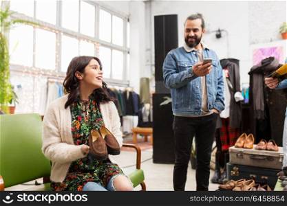 sale, shopping, footwear and people concept - happy couple choosing loafer shoes at vintage clothing store. couple choosing footwear at vintage clothing store