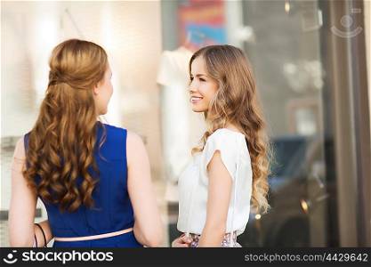 sale, shopping, friendship, consumerism and people concept - two happy women talking at shop window