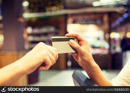 sale, shopping, payment, consumerism and people concept - close up of hands giving credit card at checkout in market or mall