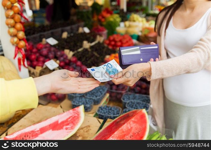 sale, shopping, pregnancy and people concept - close up of pregnant woman with wallet and money buying food at street market