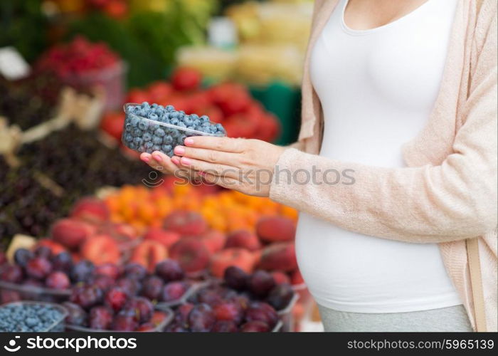 sale, shopping, pregnancy and people concept - close up of pregnant woman choosing blueberries at street food market