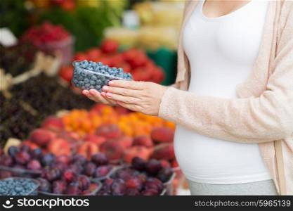 sale, shopping, pregnancy and people concept - close up of pregnant woman choosing blueberries at street food market