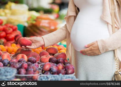 sale, shopping, pregnancy and people concept - close up of pregnant woman choosing saturn peaches at street food market