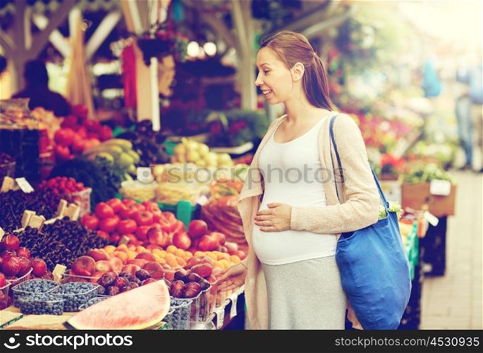 sale, shopping, pregnancy and people concept - happy pregnant woman choosing food at street market