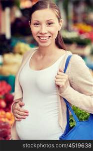 sale, shopping, pregnancy and people concept - happy pregnant woman with bag at street market