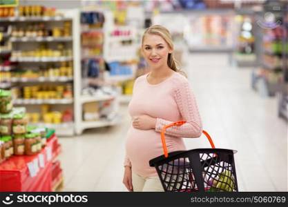 sale, shopping, pregnancy and people concept - happy pregnant woman with basket at grocery store or supermarket. pregnant woman with shopping basket at grocery