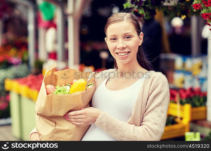 sale, shopping, pregnancy and people concept - happy pregnant woman with paper bag full of food at street market