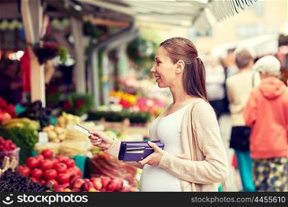 sale, shopping, pregnancy and people concept - happy pregnant woman with wallet and credit card buying food at street market
