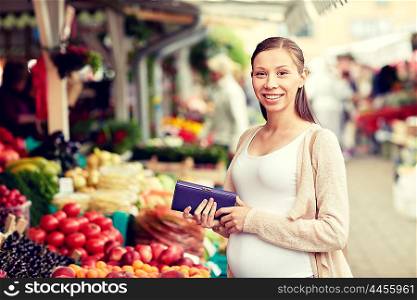 sale, shopping, pregnancy and people concept - happy pregnant woman with wallet and money buying food at street market