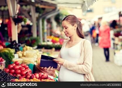 sale, shopping, pregnancy and people concept - happy pregnant woman with wallet buying food at street market