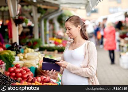 sale, shopping, pregnancy and people concept - happy pregnant woman with wallet buying food at street market
