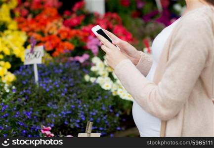 sale, shopping, pregnancy, gardening and people concept - close up of pregnant woman with smartphone at street flower market