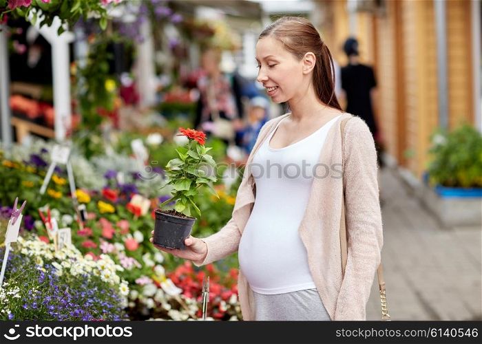 sale, shopping, pregnancy, gardening and people concept - happy pregnant woman choosing flowers at street market