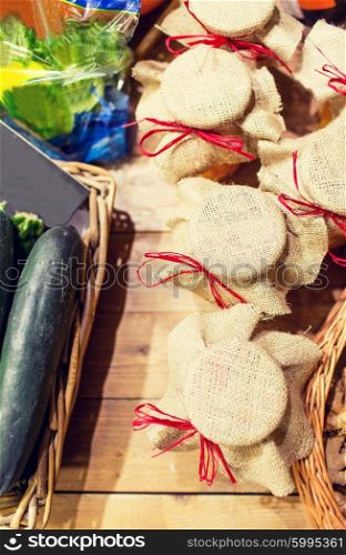 sale, shopping, rustic style and eco food concept - honey jars decorated with sackcloth and vegetables at bio market