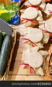 sale, shopping, rustic style and eco food concept - honey jars decorated with sackcloth and vegetables at bio market