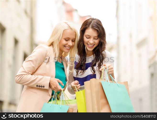 sale, shopping, tourism and happy people concept - two beautiful women looking inside shopping bags in the ctiy