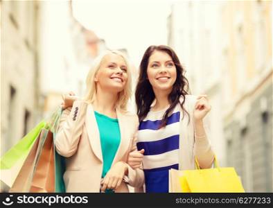 sale, shopping, tourism and happy people concept - two beautiful women with shopping bags in the ctiy