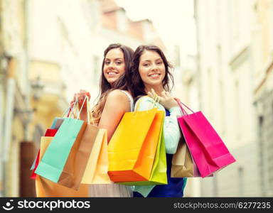 sale, shopping, tourism and happy people concept - two beautiful women with shopping bags in the ctiy