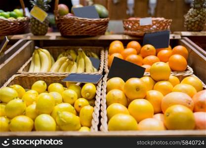 sale, shopping, vitamin c and eco food concept - ripe fruits in baskets with nameplates at grocery market