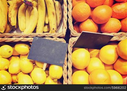 sale, shopping, vitamin c and eco food concept - ripe fruits in baskets with nameplates at grocery market