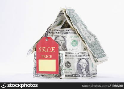 Sale tag attached with a miniature house made up of US dollar bills
