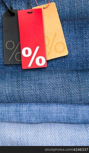 Sale Tags With Percentage Symbol on Stack of Blue Jeans