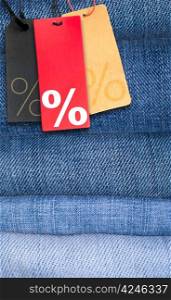 Sale Tags With Percentage Symbol on Stack of Blue Jeans