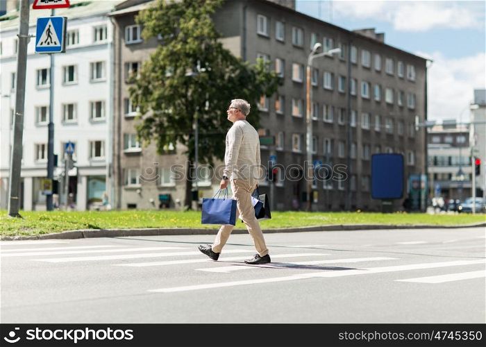 sale, traffic and people concept - senior man with shopping bags walking along city crosswalk